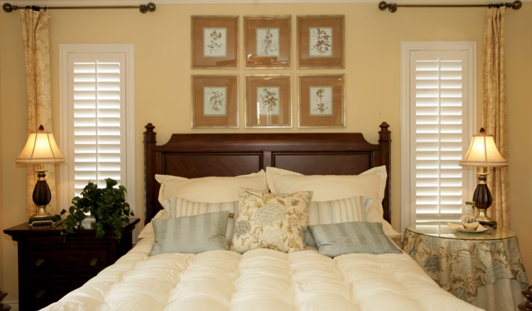 Tall plantation shutters framing bed in a bedroom in San Antonio 